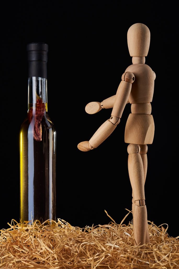 Fotografía de Producto- Botella de aceite de oliva con muñeco de madera, iluminada en estudio.